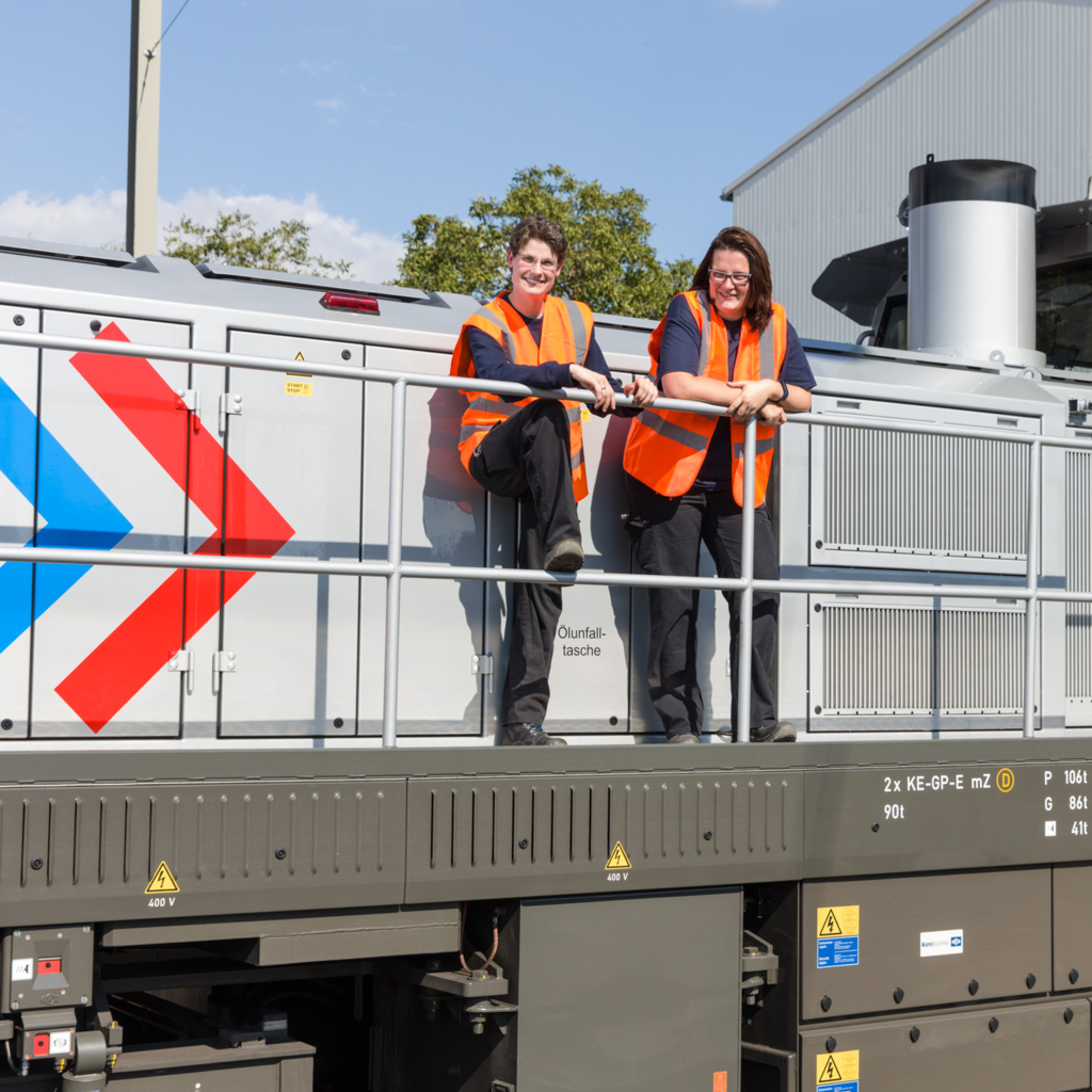 Foto zweier Mitarbeiterinnen der RheinCargo in Signalwesten auf einer Lok