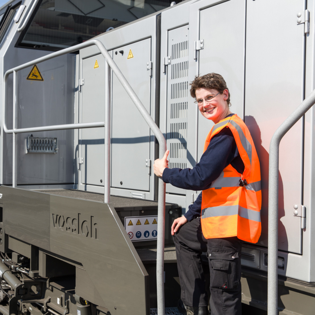Foto einer Mitarbeiterin der RheinCargo in Signalweste auf einer Lok