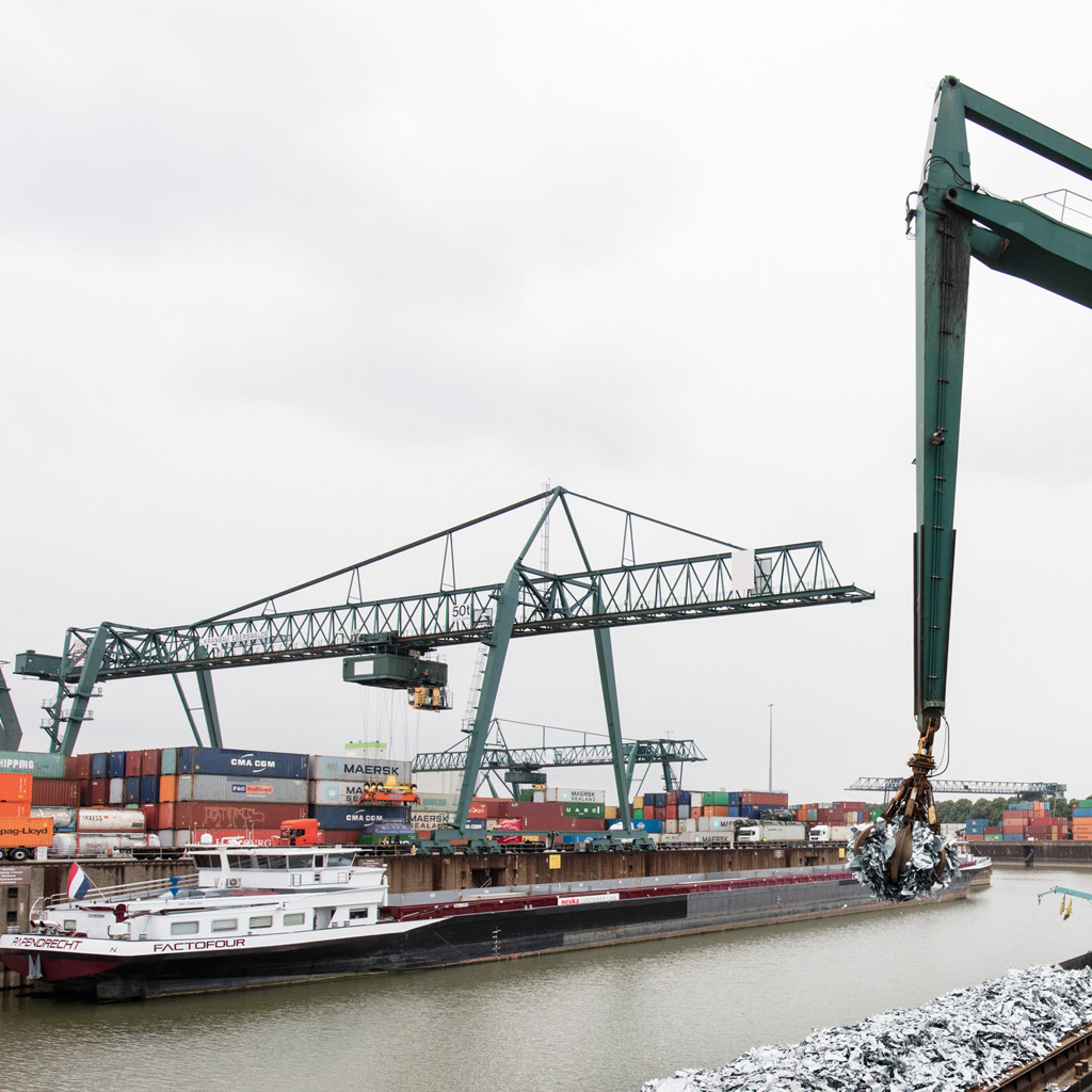 Foto eines Krans im Hafen, der Recycling-Material in ein Frachtschiff lädt