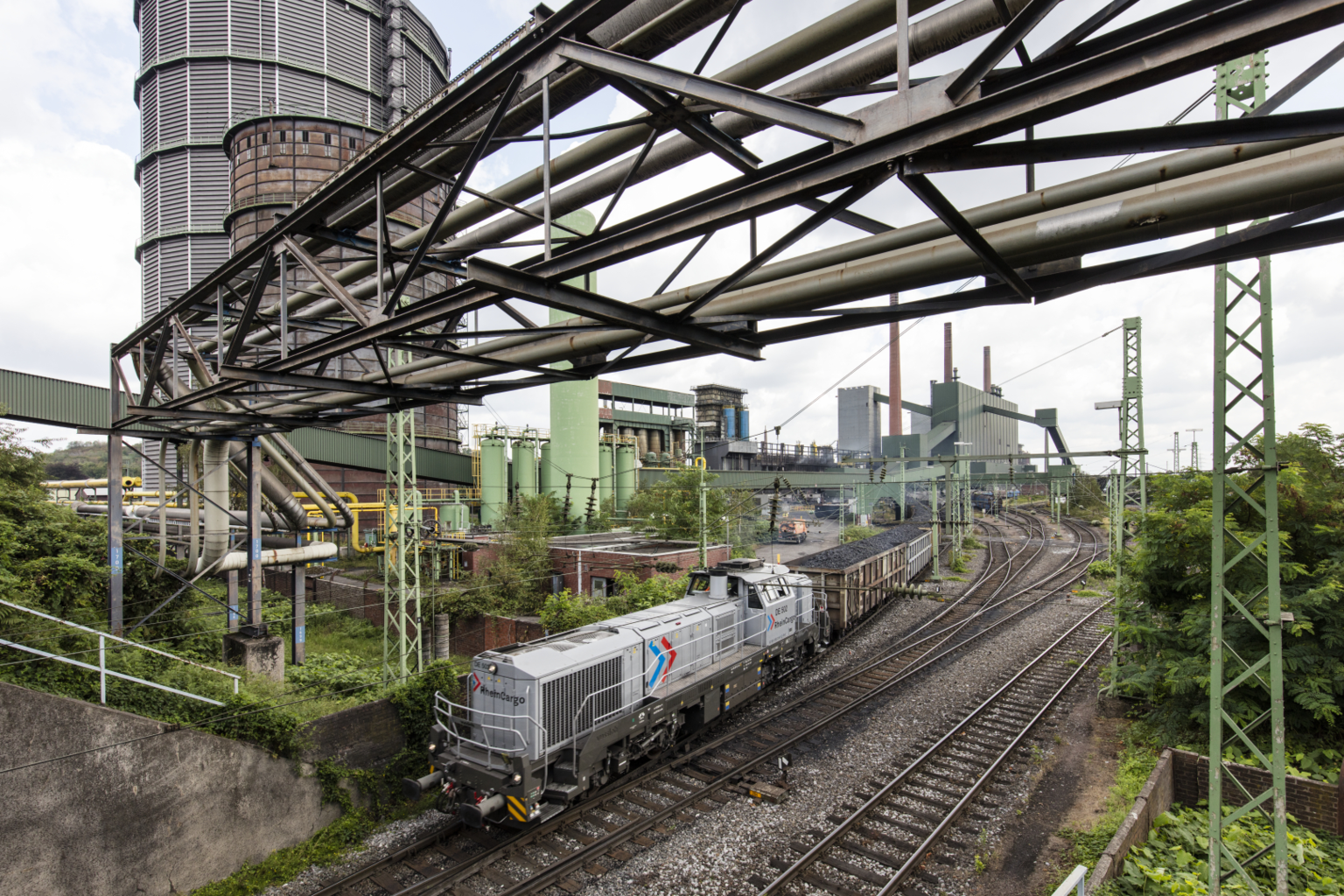 Güterzug von RheinCargo auf Gleisanlage eines Industriegeländes.