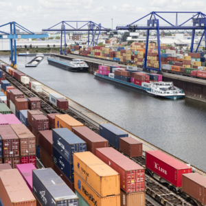 Intermodaler Containerhafen mit Frachtschiffen, Containerkränen und zahlreichen Containern, die auf Schienen und Wasserwegen verladen werden.